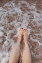 Travel concept - Woman& x27;s legs on beautiful tropical beach with pebble sand. Feet on sand and wave in summer time