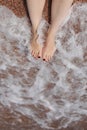 Travel concept - Woman& x27;s legs on beautiful tropical beach with pebble sand. Feet on sand and wave in summer time