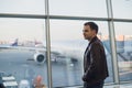 Travel concept with young man in airport interior with city view and a plane flying by. Royalty Free Stock Photo