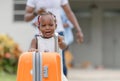 Travel concepts, Orange luggage with blurred cheerful african american girl and parent family leaving house for vacation