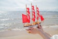 Travel and cruise concept. Ship with red sails against sea, beach and sky clouds