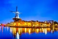 Travel Destinations. Night View of Harlem Sight With De Adriaan Windmill on Spaarne River On The Background During Blue Hour