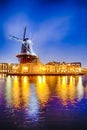 Travel Destinations. Night View of Harlem Sight With De Adriaan Windmill on Spaarne River On The Background During Blue Hour