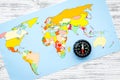 Travel direction and trip planning concept with compass and map of the world on gray wooden background top view Royalty Free Stock Photo