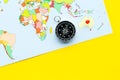 Travel direction and trip planning concept with compass and map of the world on yellow background top view space for Royalty Free Stock Photo