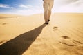 Travel and explore people concept with man viewed from back walking in tha sand of the desert dunes alone under the sunset - Royalty Free Stock Photo