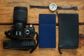 Travel flatlay on brown wooden background with camera, international passports, wallet and compass