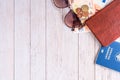 Travel flatlay: passport, pocketbook, money and sunglasses on the corner on beige boards