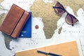 Travel flatlay: wallet, pocketbook, passport, pen and sunglasses on the world map on background