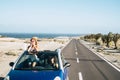 Travel friends and transport with blue convertible car and couple of adult women friends have fun together driving on a long road