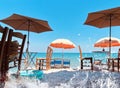 Travel Greece Sea Wave Water Splash Pink Umbrellas And Wooden Deck Chairs Wooden Table On The Bed Blue Sky  , White Sand On Beach