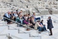 Travel guide with group of tourists sitting on ancient steps