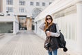 Travel happy time in modern city centre of yoyful pretty young woman in sunglasses, warm winter woolen sweater, knitted Royalty Free Stock Photo