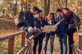 Group of young friends hiking in autumn colorful forest, looking at map and planning hike. Royalty Free Stock Photo