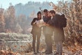 Group of young friends hiking in autumn colorful forest, looking at map and planning hike. Royalty Free Stock Photo