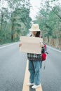 Travel hitchhiker woman holding sign with hat and backpack standing on a road Royalty Free Stock Photo