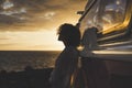 Travel and independence concept with woman in silouette and old vintage camper van - coloured dawn sunset in background with ocean Royalty Free Stock Photo