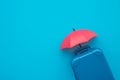 Travel insurance business concept. Red umbrella cover suitcases travelers on blue background copy space. Travel insurance coverage