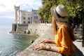 Travel in Italy. Back view of beautiful girl visiting Miramare Castle in Trieste, Italy