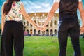 Travel in Italy Rome, Colosseum. Engaged couple tourists walking hand by hand in the historic center of the city, seen from behind