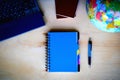 Travel items, blue notepad, pen, pc, globe on wooden background Royalty Free Stock Photo