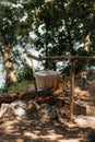 Travel a kettle over a fire burning on the river and sunset backgroun. Cooking over a campfire.