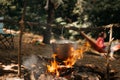 Travel a kettle over a fire burning on the river and sunset backgroun. Cooking over a campfire. Royalty Free Stock Photo