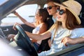 Friends rented a car for summer road trip to the beach. Female driver in glasses and straw hat having fun. Woman learned