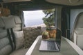 Travel lifestyle and online digital nomad workplace inside modern camper van. Laptop computer on the table and nature outside the Royalty Free Stock Photo
