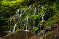 Excited Caucasian woman standing on the rock, raising arms in front of waterfall. View from back. Banyu Wana Amertha waterfall Royalty Free Stock Photo