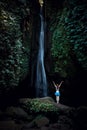 Excited Caucasian woman raising arms in front of waterfall. View from back. Leke Leke waterfall, Bali, Indonesia Royalty Free Stock Photo