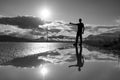 Travel man hitchhiking. Reflection in a puddle. Silhouette of man with a raised hand thumb up