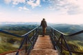 Travel man tourist alone on the edge viewing platform or observation point made from metal over amazing epic valley mountains