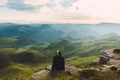 Travel man tourist sitting alone on the edge mountains over green valley adventure lifestyle extreme vacations green landscape Royalty Free Stock Photo