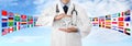 Travel medical insurance concept, doctor`s hands protect an airplane on blue sky background with flags, web banner