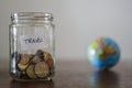 Travel money savings in a glass jar with earth globe on the background Royalty Free Stock Photo