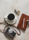 Travel mood - a cup of coffee, a retro-style camera, a notebook on a marble table in a cafe, top view Royalty Free Stock Photo