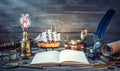 Travel and nautical theme grunge background. Old book, compass, telescope, divider, coins, shell, map, hourglass, quill pen on Royalty Free Stock Photo