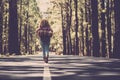 Travel people alternative backpack freedom concept with woman walking alone in the middle of the asphalt road and forest woods in