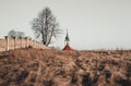 Travel photo of old Christian church chapel near the cemetery on meadow. Church with tree with burnt grass on sunset. View on Royalty Free Stock Photo