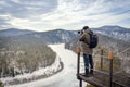 A travel photographer photographs a winter landscape in early spring, the frozen Mana River in Siberia, the Manskaya