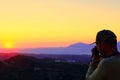 Travel photographer taking a photo of a valley at sunset