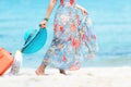 Travel Plan. Hand women traveler holding orange luggage walking on the beach. Traveler and Tourism planning trips summer vacations