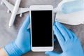 Travel planning concept, coronavirus and quarantine. Hands in disposable gloves hold smartphone Royalty Free Stock Photo