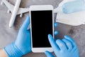Travel planning concept, coronavirus and quarantine. Hands in disposable gloves hold smartphone. Royalty Free Stock Photo