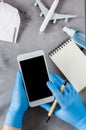 Travel planning concept, coronavirus and quarantine. Hands in disposable gloves hold smartphone and write in notebook Royalty Free Stock Photo