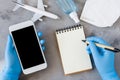 Travel planning concept, coronavirus and quarantine. Hands in disposable gloves hold smartphone and write in notebook Royalty Free Stock Photo