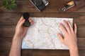 Travel planning concept. Hands holding compass with knife, vintage camera and map on wooden table Royalty Free Stock Photo