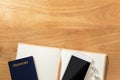 travel planning concept with passport, cellphone, earphone, pencil and open blank paper notebook on wooden table Royalty Free Stock Photo