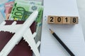 Travel planning target with toy airplane, passport, Euro banknotes with wooden block 2018 and pencil on paper note
